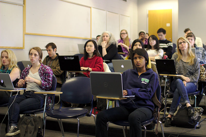 A photo of a classroom full of people on laptops. The seating is tiered, with people in the back higher up.
