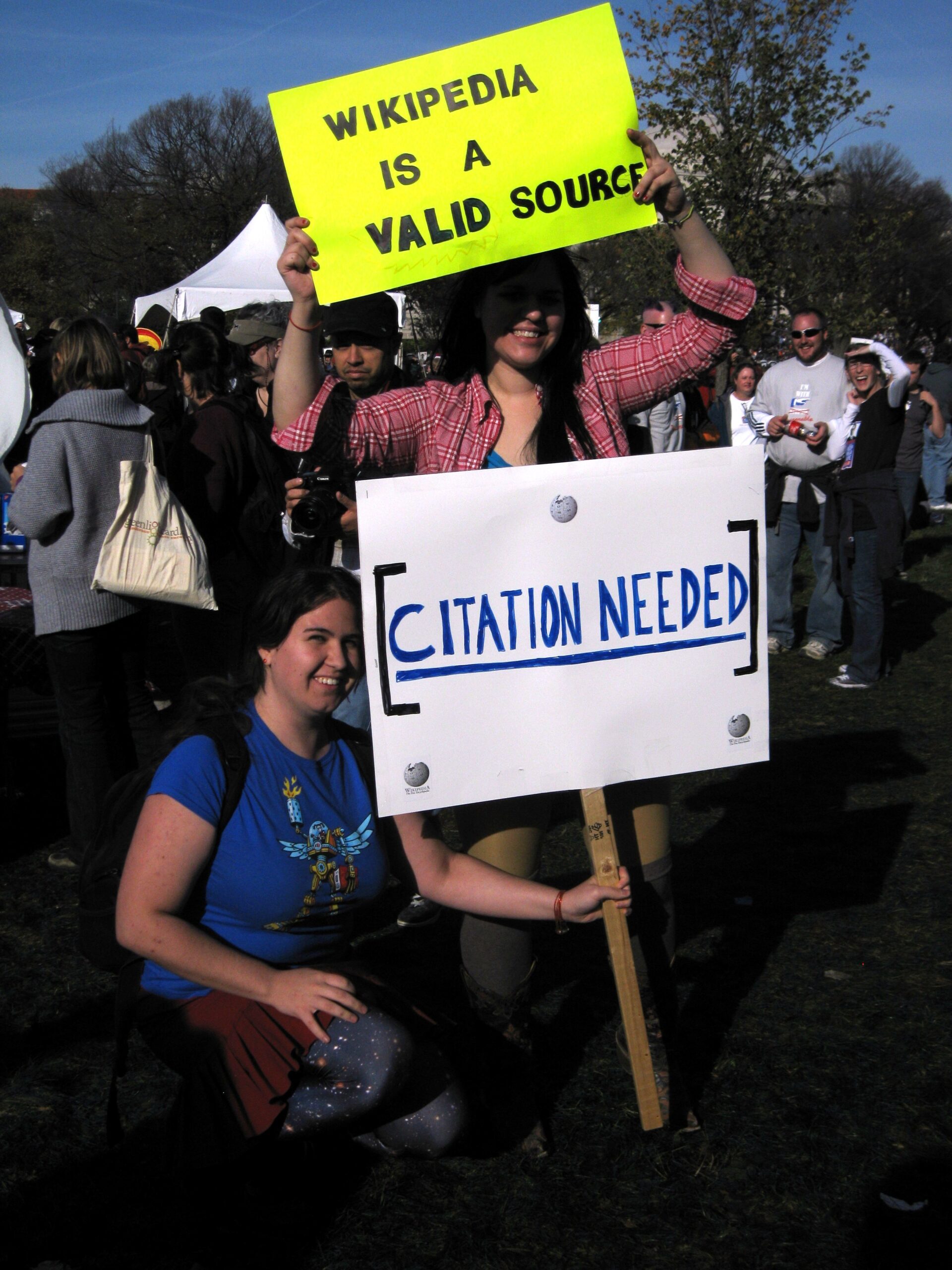 Two participants of the "Rally to Restore Sanity and/or Fear" in Washington D.C. (USA), holding signs saying "Wikipedia is a valid source" and "citation needed." Photo by Kat Walsh (Wikipedia User: Mindspillage), October 30, 2010, CC-BY-SA 3.0.
